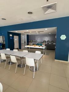 a kitchen with tables and chairs and a blue wall at One Irapuato in Irapuato