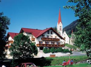 ein großes weißes Gebäude mit einer Kirche auf einem Hügel in der Unterkunft Gasthof Bären in Holzgau