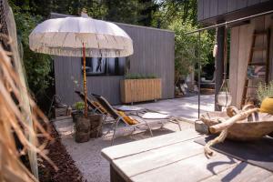 a patio with a table and an umbrella and chairs at AuxiliumWellness Get Back to Serenity in Grobbendonk