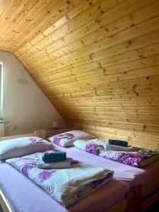 three beds in a room with a wooden ceiling at Domček u Ferka in Dedinky