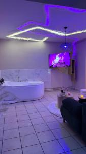 a bathroom with a tub and a tv on the wall at Romantic Suite with Private Jacuzzi in Noyon