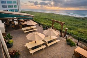 a patio with tables and umbrellas and the beach at Palms Resort & Cafe on the Beach in South Padre Island