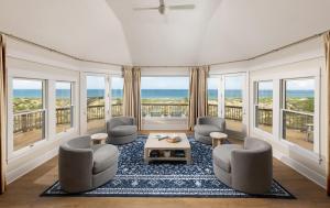 a living room with chairs and a table and windows at The Sanderling in Duck