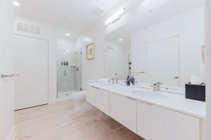 a white bathroom with two sinks and a toilet at Joinery North in Charlotte
