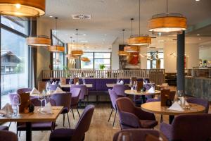 a dining room with tables and purple chairs at JUFA Hotel Werfenweng in Werfenweng