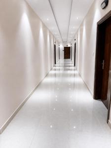 an empty hallway with white walls and white tile floors at أرياف سويت in Al Baha