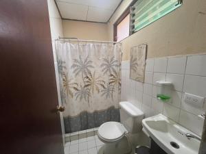 a bathroom with a toilet and a sink and a shower curtain at Hospedaje Doña koko in Puerto Limón +51 photos