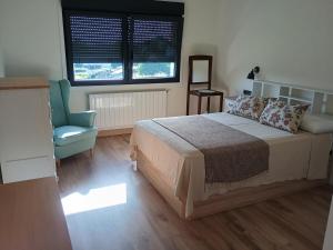 a bedroom with a bed and a chair and a window at A de Amancio in Sayáns