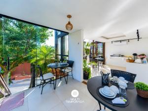a dining room with tables and chairs and a large window at Pousada Solar dos Lírios - Praia do Rosa in Praia do Rosa +95 photos