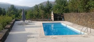 a swimming pool with an umbrella on a patio at Casa Kika e Noelle in Castanheira de Pêra