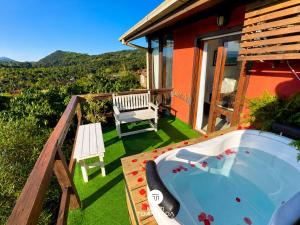 a hot tub on a deck with a bench and a house at Pousada Solar dos Lírios - Praia do Rosa in Praia do Rosa