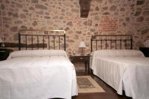 two beds with white sheets in a bedroom at APARTAMENTO RURAL ABUELO EMILIO in Tornavacas