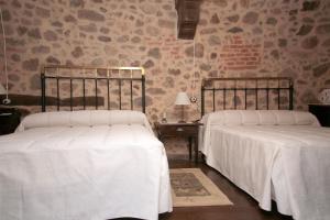 two beds with white sheets in a bedroom at APARTAMENTO RURAL ABUELO EMILIO in Tornavacas