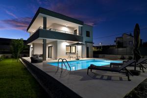 a villa with a swimming pool at night at Casa Magista in Sukošan