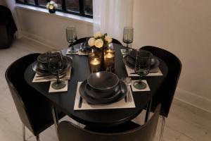 a black table with black plates and wine glasses at Newcastle City Centre 2BR, Near Central Train Station in Newcastle upon Tyne