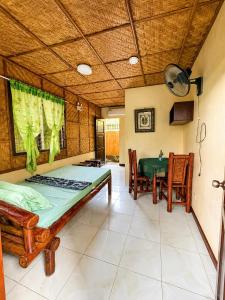 a bedroom with a bed and a table and chairs at Argana Cottages in Dauin
