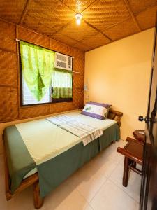 a bedroom with a large bed with a window at Argana Cottages in Dauin