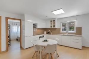a kitchen with white cabinets and a white table and chairs at Casas de Vacaciones Ibaiale in Cazadores