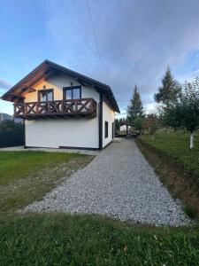 a small house with a balcony on a gravel road at Grey House in Vorokhta