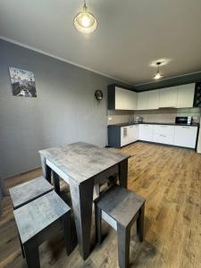 a room with a table and two benches and a kitchen at Grey House in Vorokhta