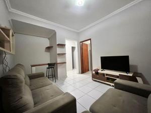 a living room with a couch and a flat screen tv at Veneza Exclusive 101 in Ipatinga