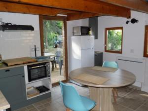 a kitchen and dining room with a table and blue chairs at L'erable in Montlay-en-Auxois