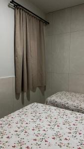 a bedroom with a bed with a floral bedspread and a window at Central APE Diamantina in Diamantina