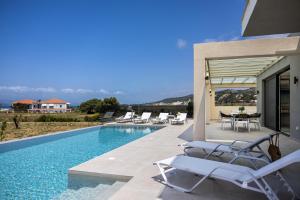 a house with a swimming pool with chairs and a table at TATOLI Villas in Minia
