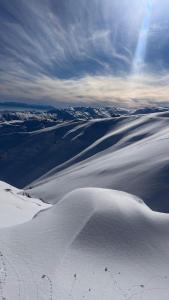 a snow covered mountain with the sun in the sky at Para 6 pax La Parva in Lo Barnechea