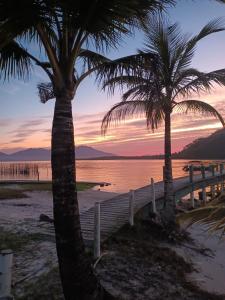 two palm trees on the beach at sunset at Toca do Caranguejo-Iate Clube Rio Verde - Ilha Comprida in Cananéia