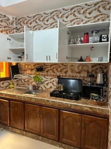 a kitchen with a counter with a sink and a microwave at Jannat Résidence in Ouarzazate +36 photos
