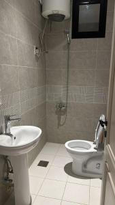 a bathroom with a toilet and a sink at عالم الضيافة in Al ‘Azīzīyah
