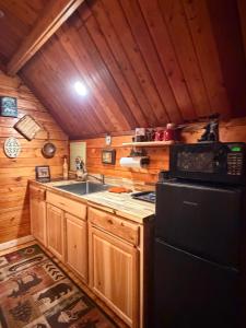 a kitchen with a sink and a stove and a refrigerator at Big Bear Log cabin in Cosby