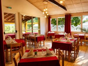a restaurant with red tables and chairs and windows at Les Chênes verts in Saint-Savinien