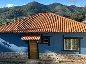 a blue house with a window and mountains in the background at Cataventooo hospedagens in Miguel Pereira