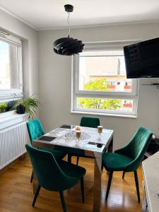 a dining room with a table and green chairs at STUDIO HETMANSKA H15 ElBląg in Elblag