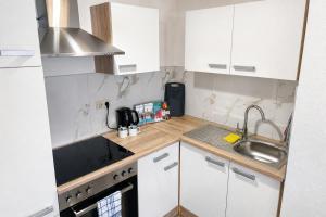 a small kitchen with white cabinets and a sink at NOBLE APART Saarbrücken City Center in Saarbrücken +10 photos