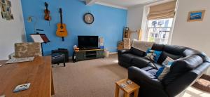 a living room with a leather couch and a tv at Sailor's Rest in Anstruther +4 photos