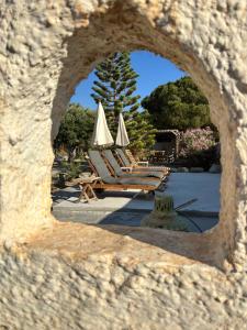 a view of lounge chairs and umbrellas through a stone window at 7olives Golden Boutique Apartment in Kastraki