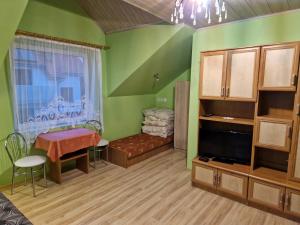 ein grünes Zimmer mit einem Tisch und einem Fenster in der Unterkunft Willa Elf in Karwia