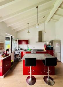 a kitchen with red cabinets and a counter with two bar stools at La Casita cerca de la playa in Santander