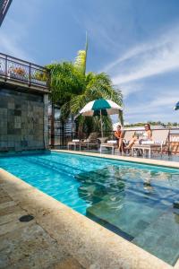 two women sitting under an umbrella next to a swimming pool at Hotel Capellán de Getsemaní in Cartagena de Indias