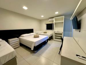 a hotel room with two beds and a television at Pousada Alphaville in Palmas