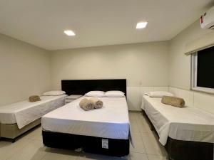 a room with two beds in a room with a window at Pousada Alphaville in Palmas
