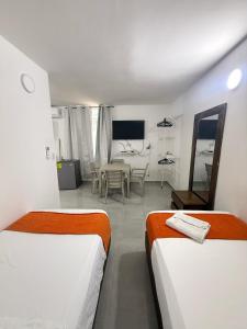 a bedroom with two beds and a dining room at Caribe 102-1 in San Andrés
