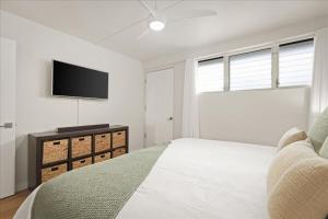 a white bedroom with a bed and a flat screen tv at Puako Beach Condo 210 - 3 Bedrooms in Waikoloa