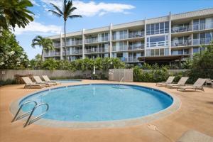 a swimming pool with lounge chairs and a building at Puako Beach Condo 210 - 3 Bedrooms in Waikoloa