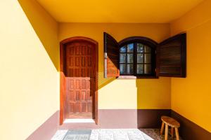 a house with a door and a window and a stool at Pousada Sonho Verde in Monte Verde