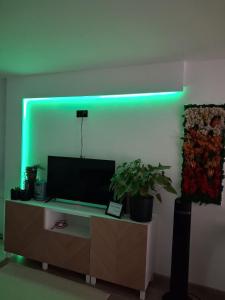 a green light on a wall with a tv on a cabinet at Apartament Drzymały in Lubin