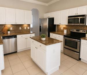 a kitchen with white cabinets and stainless steel appliances at The Garden, Miami Lakes in Miami Lakes